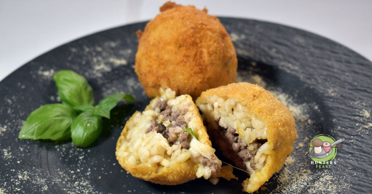 2 wild boar arancinis on black plate